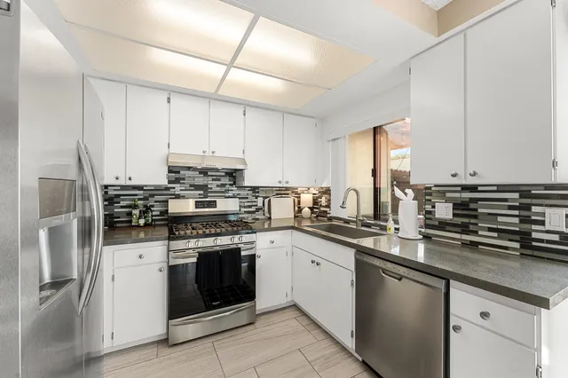 a kitchen with stainless steel appliances granite countertop a stove sink and cabinets