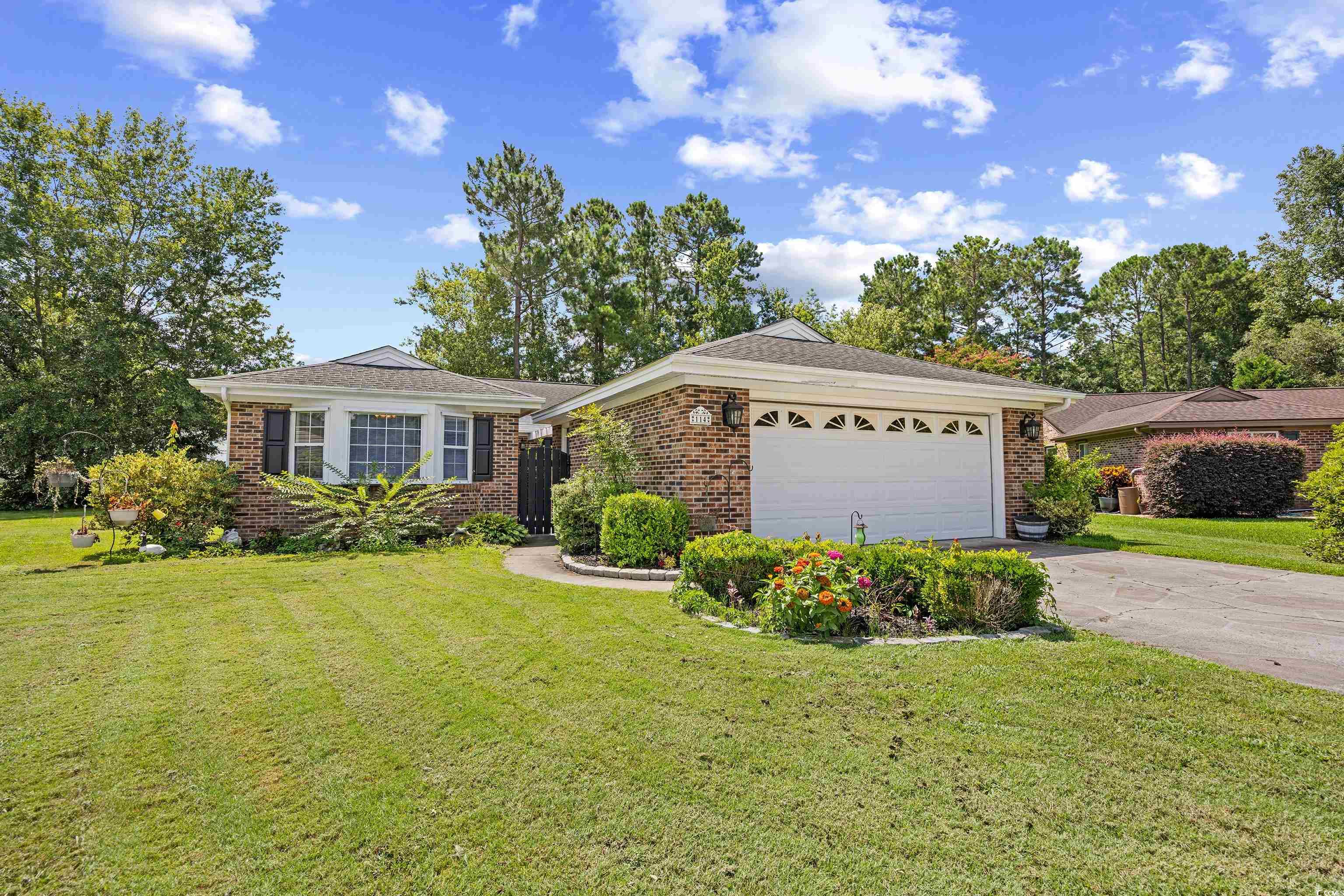 Ranch-style home with driveway, brick siding, a garage, and a front yard