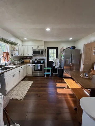 a kitchen with stainless steel appliances granite countertop a stove top oven a sink dishwasher and cabinets with wooden floor