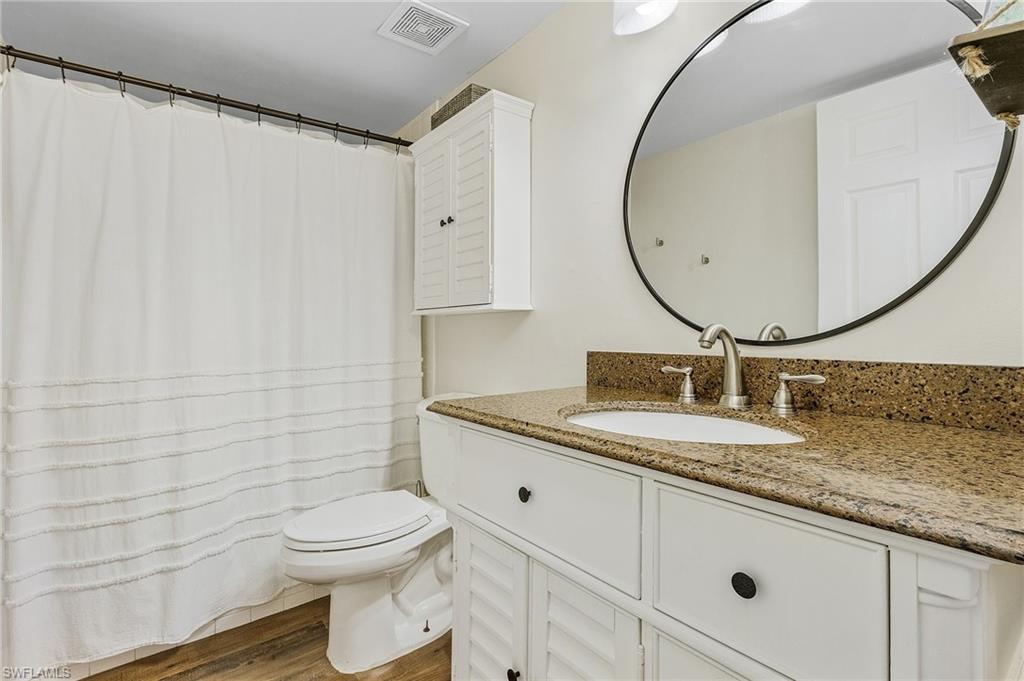 5789 Gage Lane, Unit A 103 Naples, FL 34113 - Photo 19 of 26 a bathroom with a granite countertop toilet sink mirror and vanity