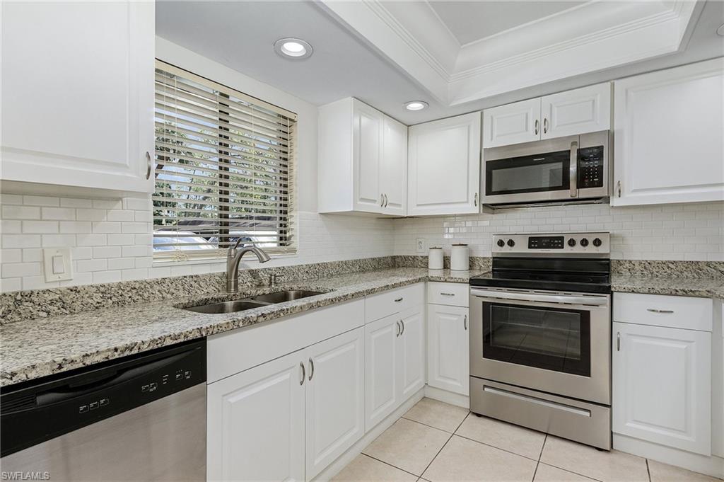 5789 Gage Lane, Unit A 103 Naples, FL 34113 - Photo 7 of 26 a kitchen with granite countertop stainless steel appliances white cabinets granite counter tops and a window