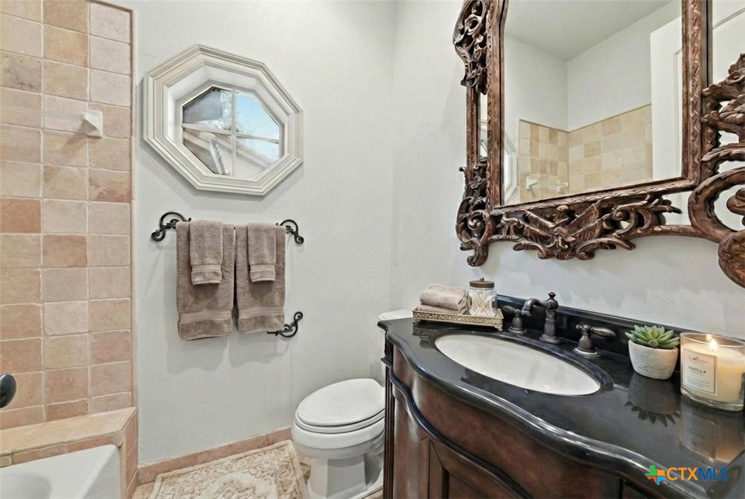 1108 Tuscan Ridge Drive New Braunfels, TX 78130 - Photo 28 of 47 a bathroom with a granite countertop toilet sink and mirror