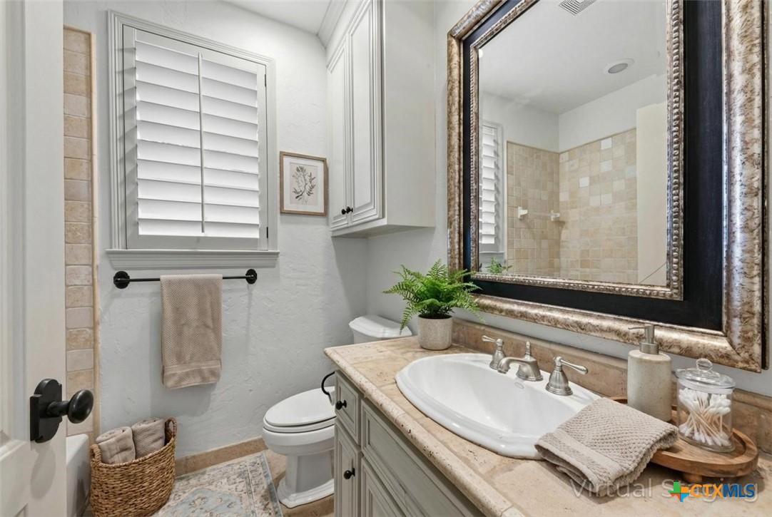 1108 Tuscan Ridge Drive New Braunfels, TX 78130 - Photo 41 of 47 a bathroom with a granite countertop toilet sink and mirror