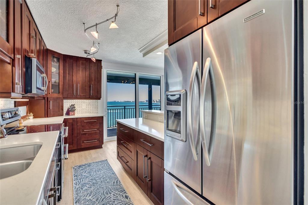 4822 Ocean Boulevard, Unit 8D Siesta Key, FL 34242 - Photo 39 of 69 a kitchen with stainless steel appliances granite countertop a refrigerator a sink dishwasher a stove and white countertops with wooden floor