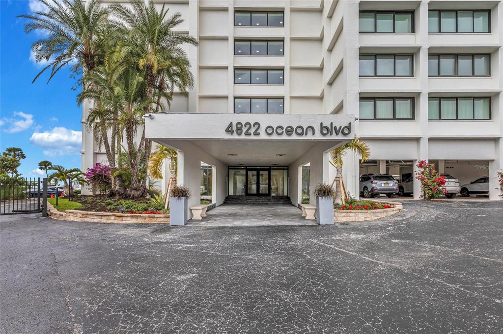 4822 Ocean Boulevard, Unit 8D Siesta Key, FL 34242 - Photo 6 of 69 a front view of multi story residential apartment building with yard and large trees