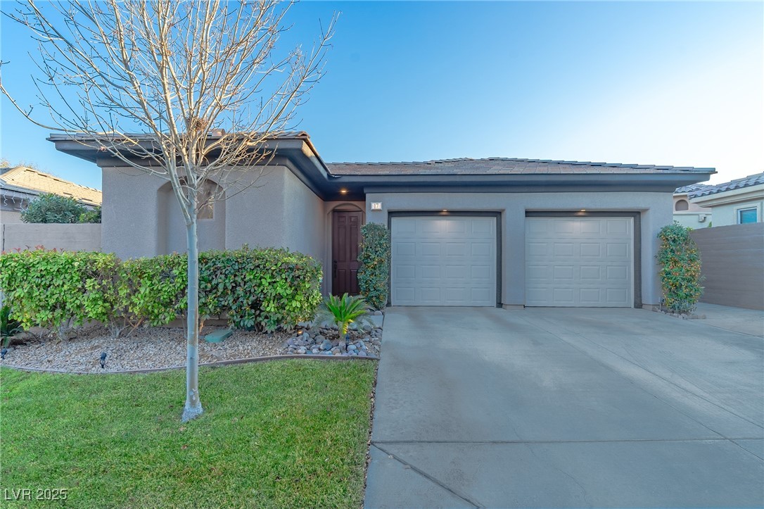 Ranch-style house with a garage, a front lawn, stucco siding, and concrete driveway