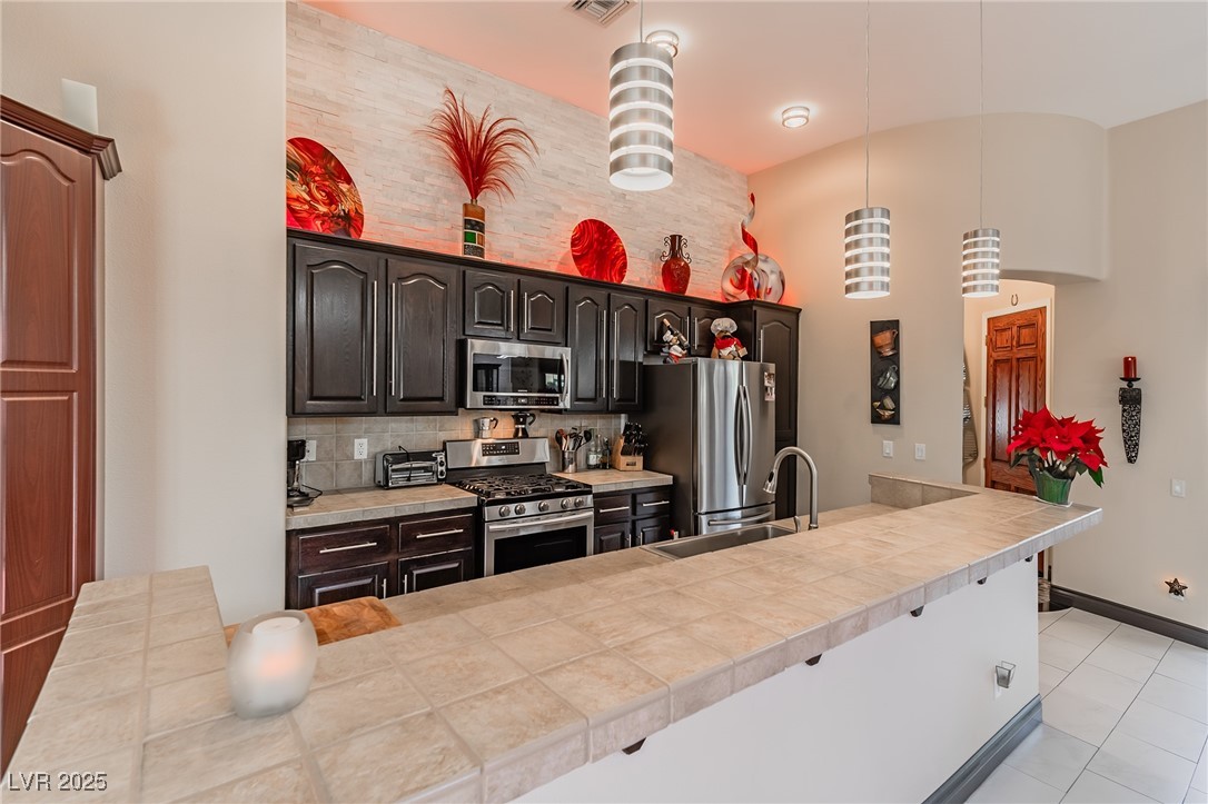 17 Chatmoss Road Henderson, NV 89052 - Photo 15 of 58 Kitchen featuring light tile patterned floors, a sink, high vaulted ceiling, and appliances with stainless steel finishes
