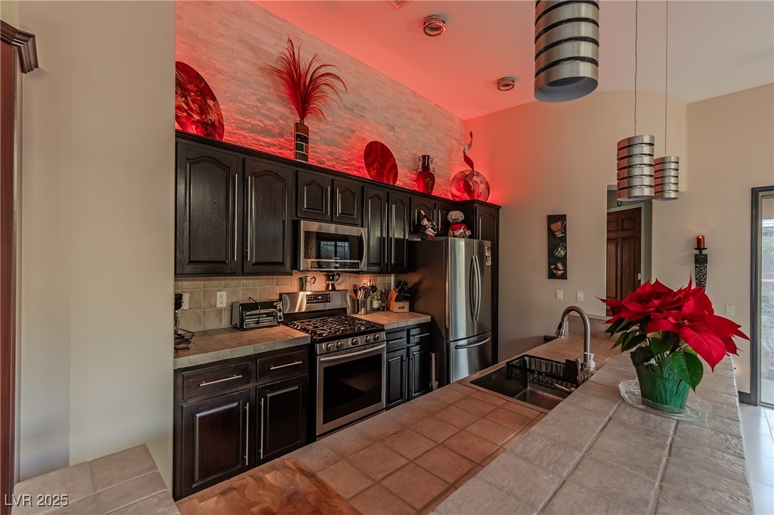 17 Chatmoss Road Henderson, NV 89052 - Photo 36 of 58 Kitchen with appliances with stainless steel finishes, tile counters, tile patterned flooring, and a sink