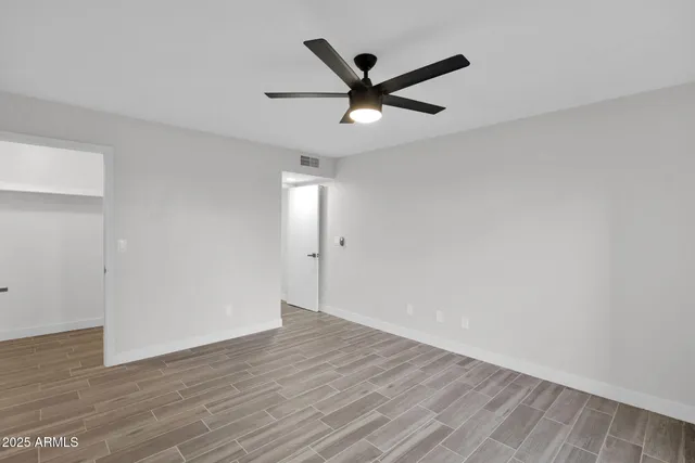 an empty room with wooden floor and windows