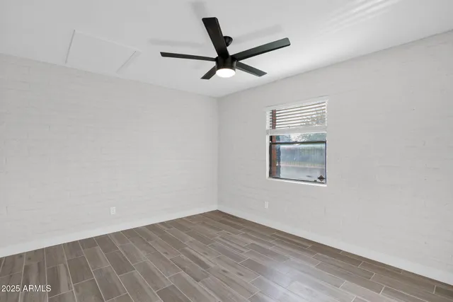an empty room with wooden floor ceiling fan and windows