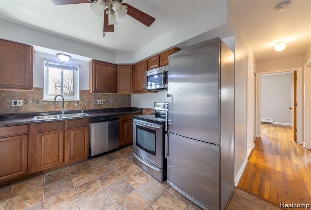 100 West Hickory Grove Road, Unit B3 Bloomfield Hills, MI 48304 - Photo 4 of 11 Kitchen featuring stainless steel appliances, wood finish cabinets, dark countertops, and decorative backsplash