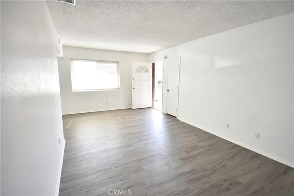 an empty room with wooden floor cabinet and windows