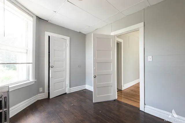 an empty room with wooden floor & windows