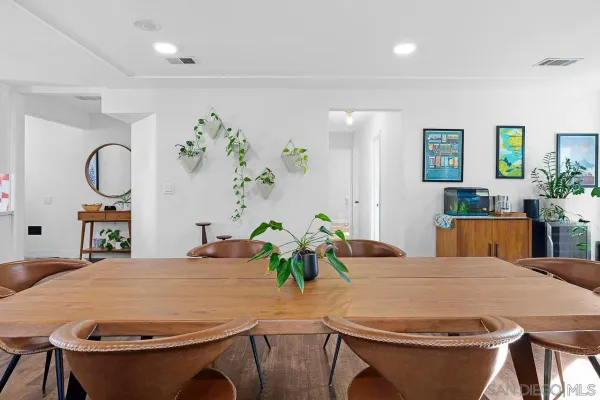 a dining room with furniture a potted plant and a painting
