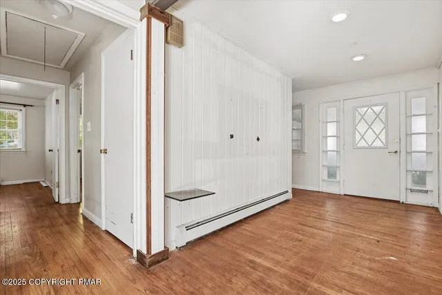a view of an empty room with wooden floor and a window