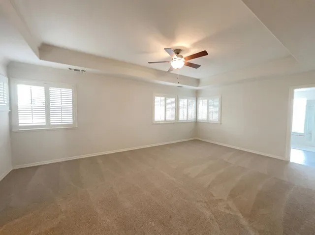 an empty room with windows and ceiling fan