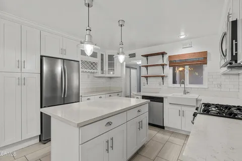 an empty room with a chandelier fan and windows