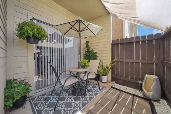 a view of a chair and table in the patio with potted plants