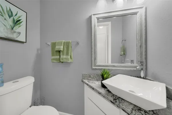 a bathroom with a granite countertop sink mirror vanity and toilet