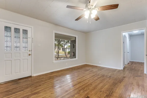 a view of an empty room with wooden floor and a window