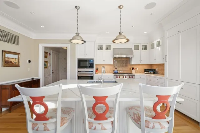 a kitchen with stainless steel appliances granite countertop a stove a sink dishwasher a dining table and chairs with wooden floor