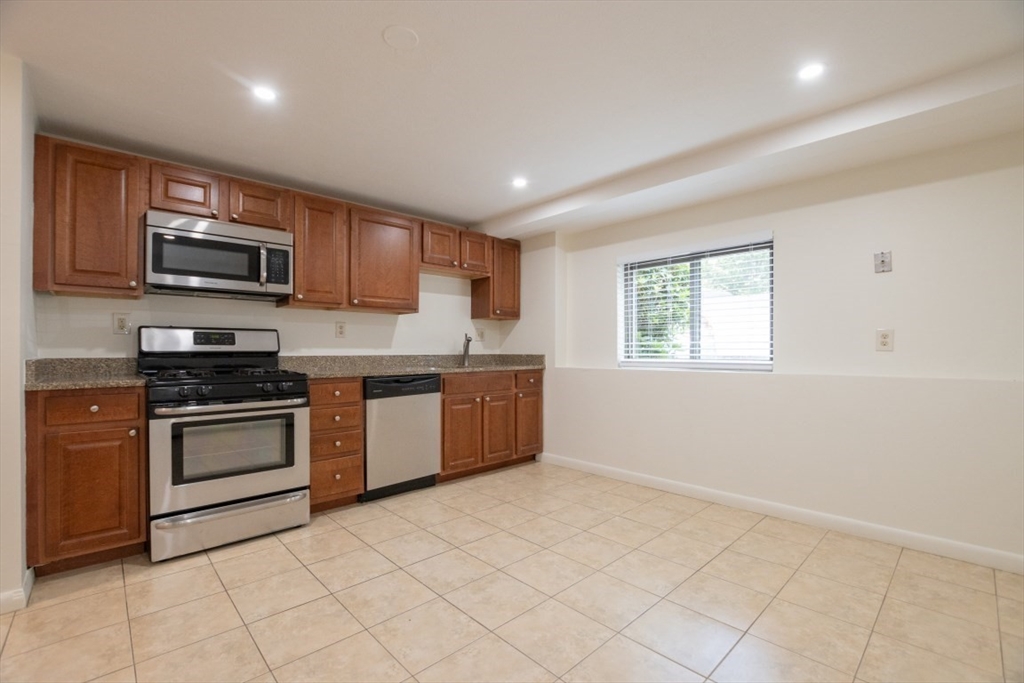 146 Willow Street, Unit 4 Waltham, MA 02453 - Photo 6 of 13 a kitchen with stainless steel appliances granite countertop a stove a sink and a microwave