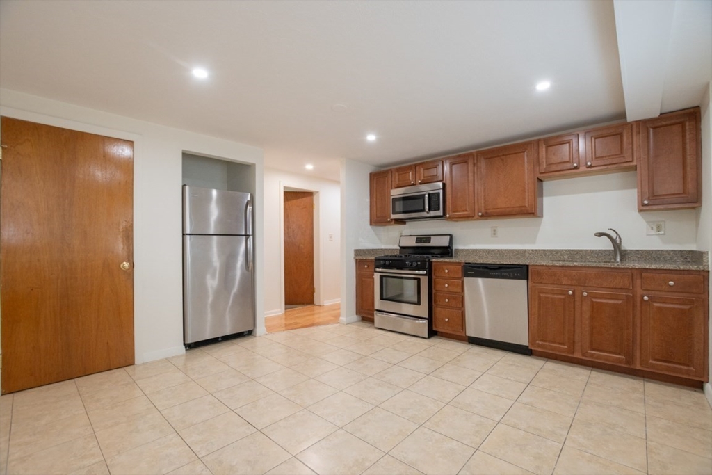 146 Willow Street, Unit 4 Waltham, MA 02453 - Photo 7 of 13 a kitchen with granite countertop a refrigerator and a stove top oven