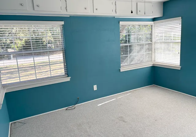 a view of a backyard with large trees and wooden fence