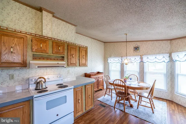 a kitchen with granite countertop a dining table chairs and wooden floor