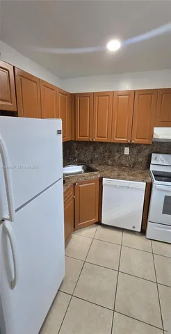 a kitchen with a white refrigerator stove and a sink
