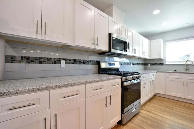 a kitchen with granite countertop white cabinets stainless steel appliances and a sink