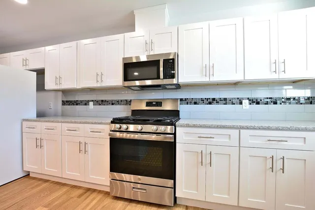 a kitchen with white cabinets and appliances