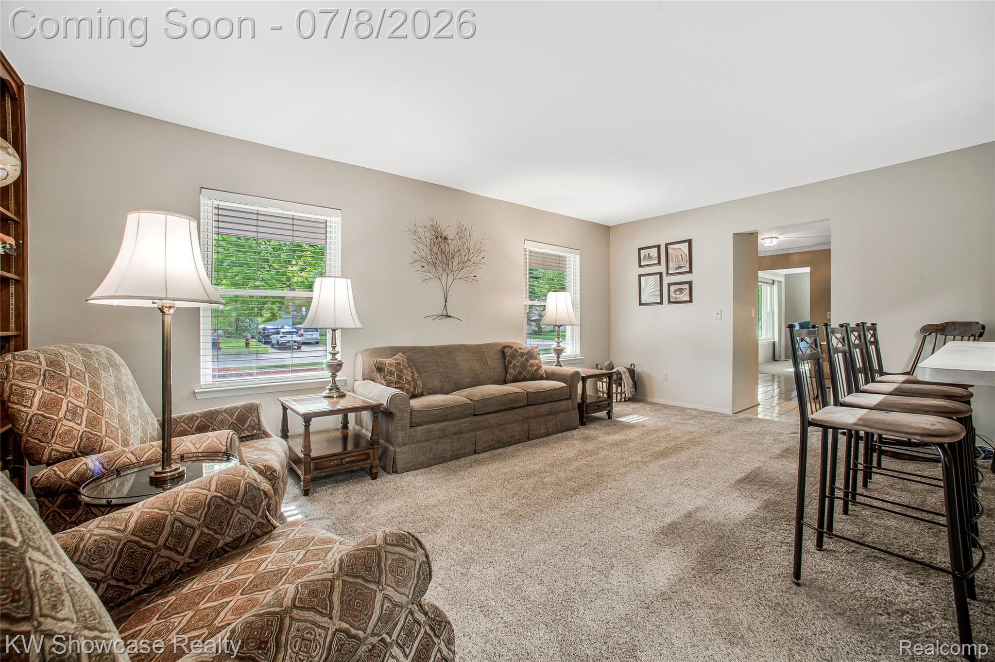 16720 Wayne Road Livonia, MI 48154 - Photo 14 of 29 Carpeted living area featuring light-toned walls, multiple windows with blinds, a built-in bookshelf, and an arched doorway leading to another room
