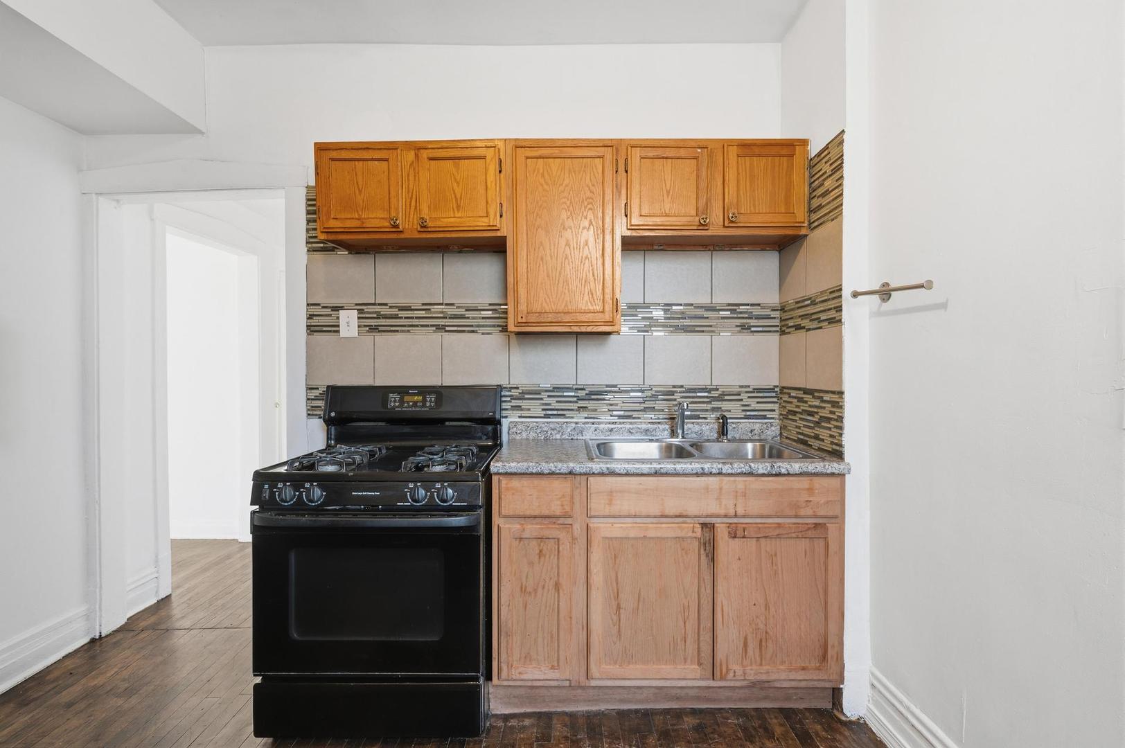 3752 West Division Street, Unit 3W Chicago, IL 60651 - Photo 4 of 11 a kitchen with white cabinets and black appliances