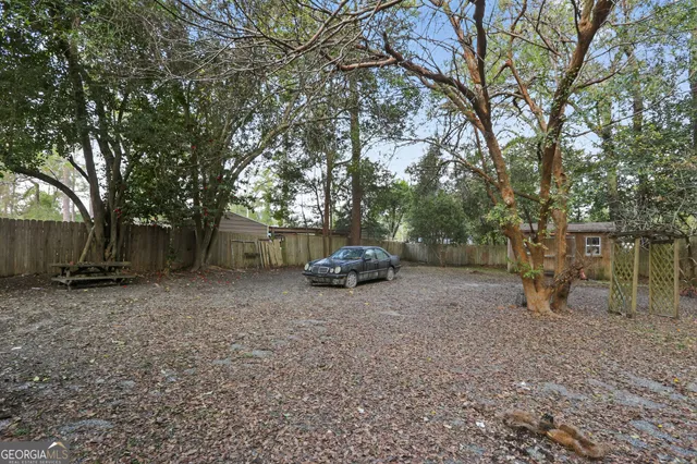 a view of a backyard with large trees and wooden fence