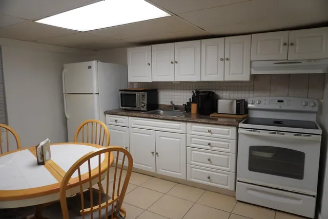 a kitchen with stainless steel appliances a stove a sink refrigerator and white cabinets
