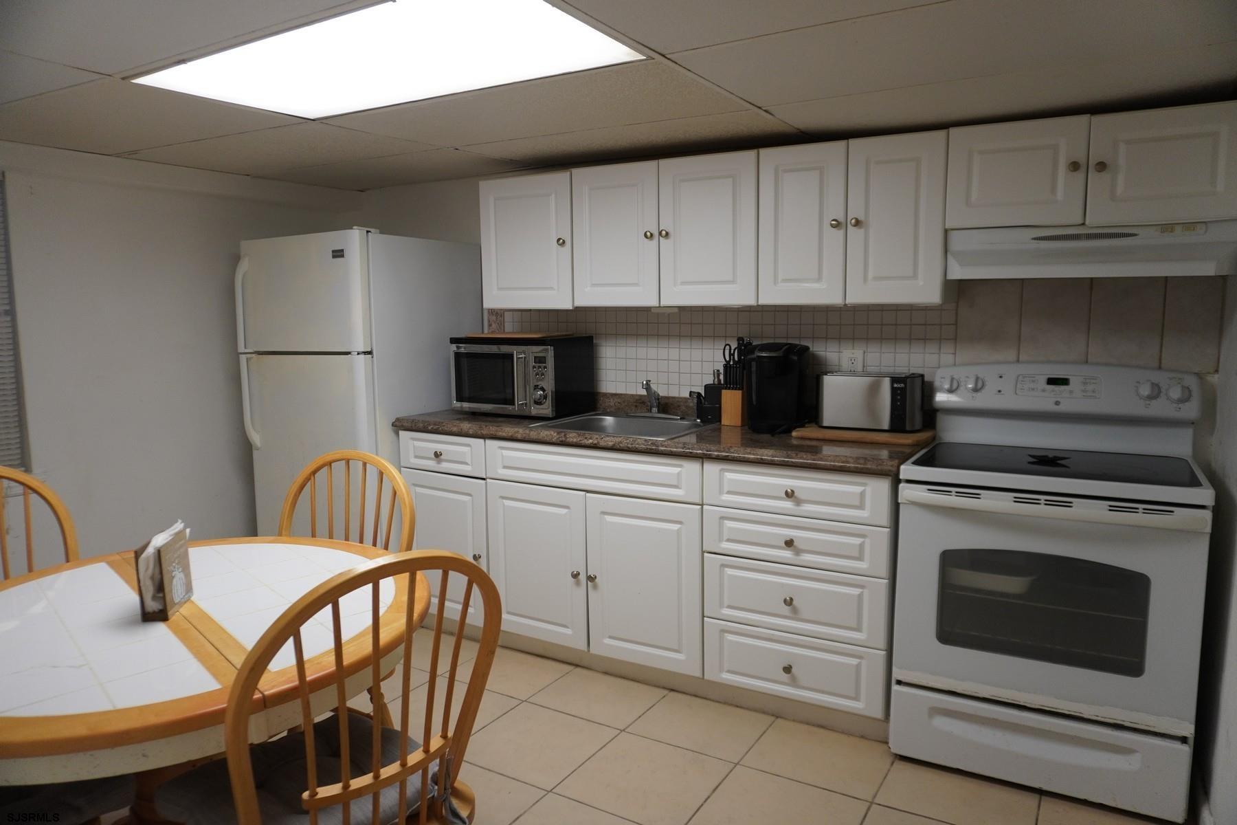 4703 Ventnor Avenue, Unit LOWER LEVEL Atlantic City, NJ 08401 - Photo 6 of 22 a kitchen with stainless steel appliances a stove a sink refrigerator and white cabinets