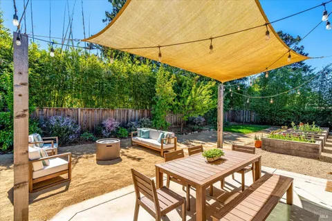 a view of patio with table and chairs potted plants and wooden fence