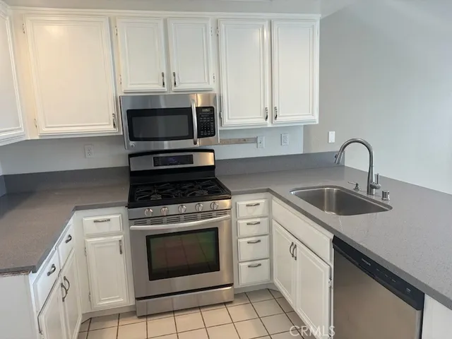 a kitchen with granite countertop white cabinets appliances and a sink