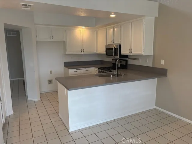 a kitchen with granite countertop white cabinets and stainless steel appliances