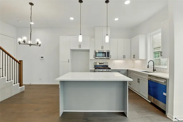 a kitchen with kitchen island a sink stainless steel appliances and cabinets