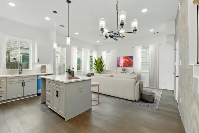 a large white kitchen with a large island oven a stove and a wooden floors
