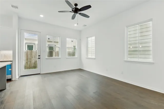 a view of an empty room with a window and wooden floor