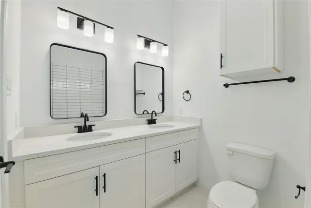 a bathroom with 2 sink toilet and mirror