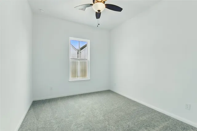 an empty room with windows and chandelier fan
