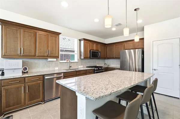 a kitchen with stainless steel appliances granite countertop a kitchen island hardwood floor sink stove and refrigerator
