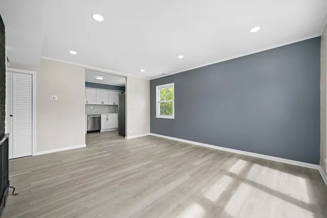 a view of empty room with wooden floor and kitchen