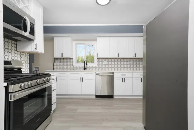 a kitchen with white cabinets and appliances