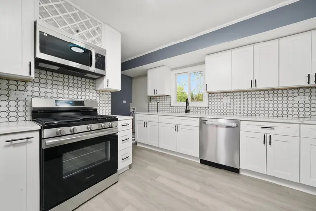 a kitchen with cabinets stainless steel appliances and wooden floor