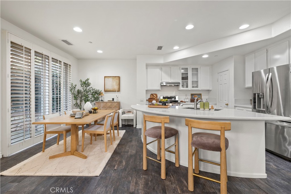 31 Poppy, Unit 50 Irvine, CA 92618 - Photo 7 of 27 a kitchen with stainless steel appliances granite countertop a table chairs refrigerator and sink